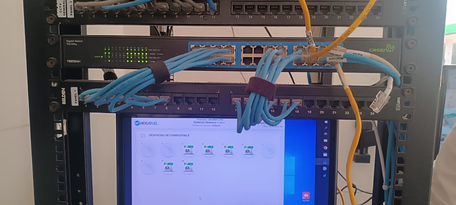Rack de red con switches, cables azules y pantalla